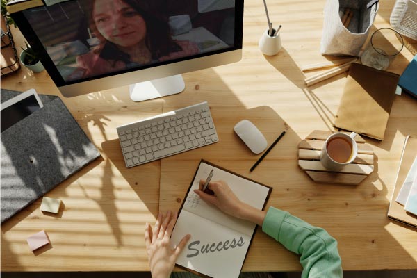 Lady on online meeting undertaking distance learning and making notes of success